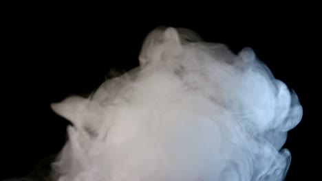 fluffy puffs of smoke and fog on black background