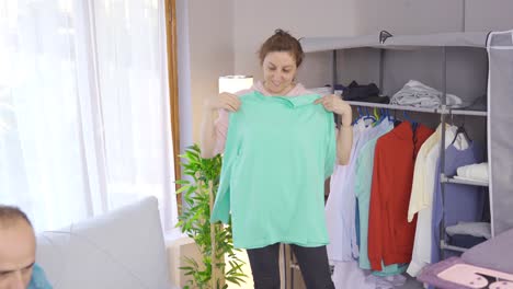 pareja casada. la mujer plancha su ropa y su marido trabaja en la computadora portátil.