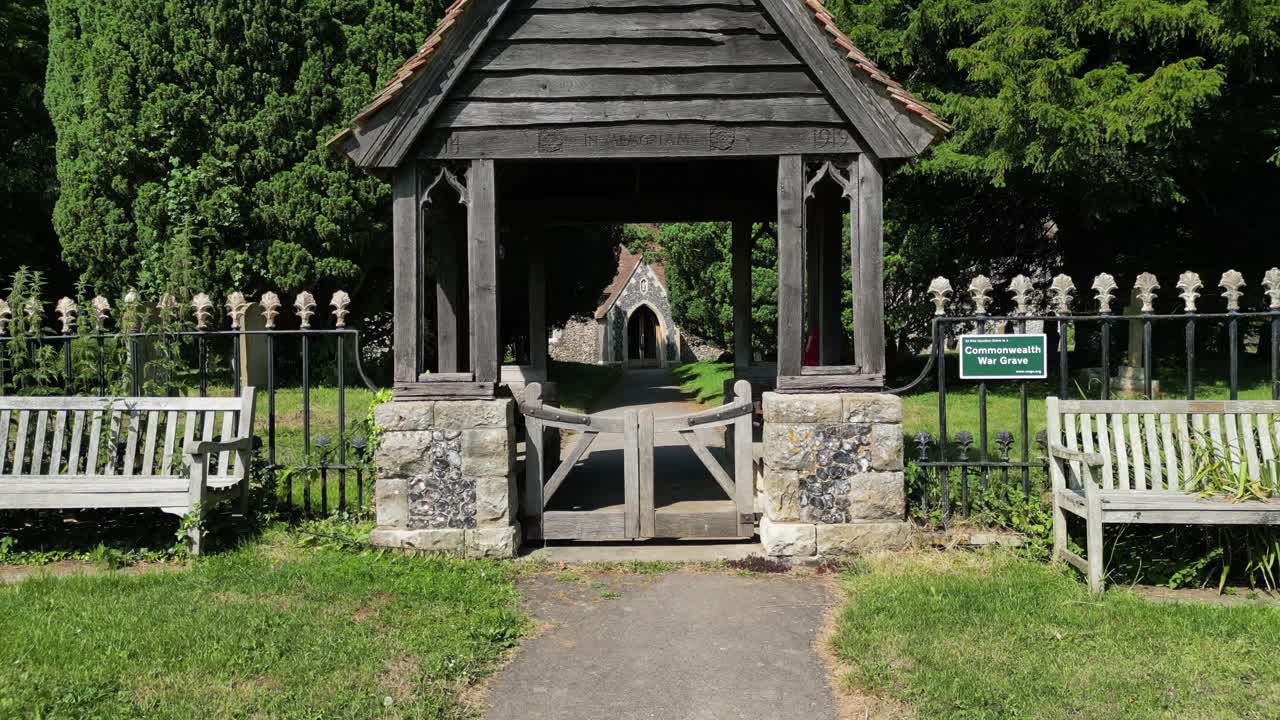 이크햄의 세인트 존 복음주의 교회 문으로 가는 길을 따라 빠른 공중 push-in  ⁇ , 울타리 뒤에 보이는 묘지