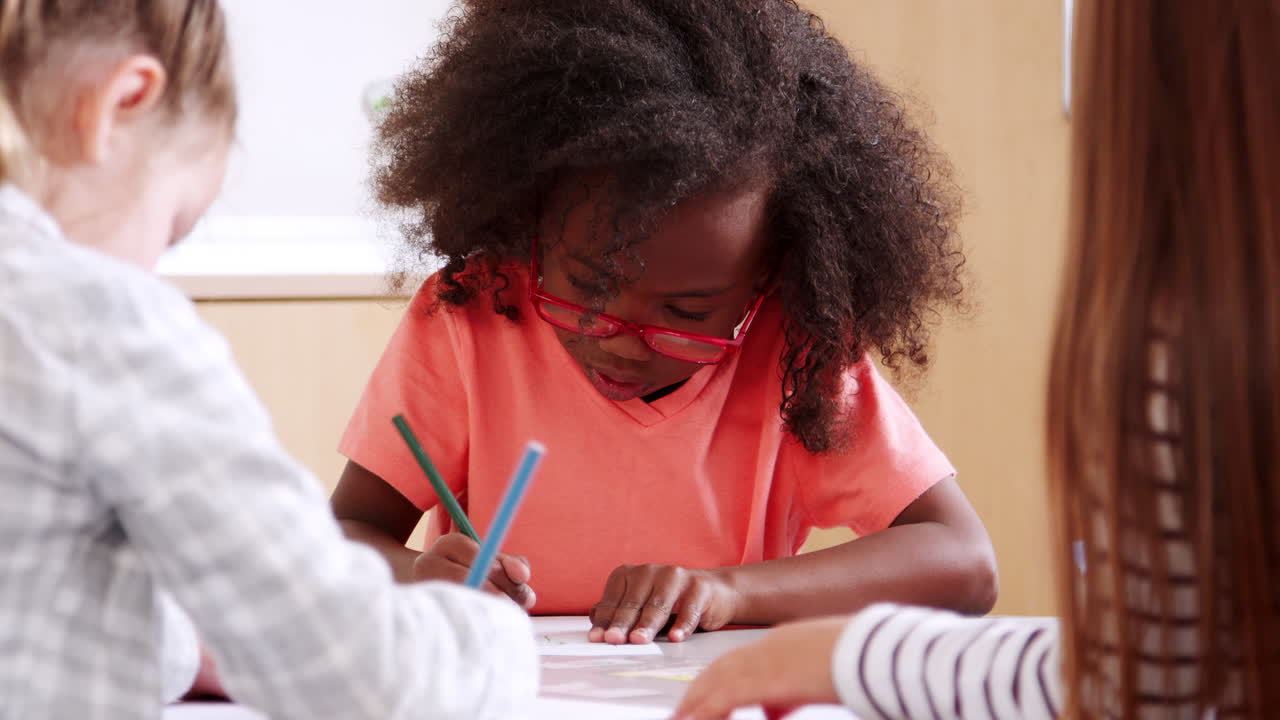 Elementary school schoolgirl in glasses drawing at art class