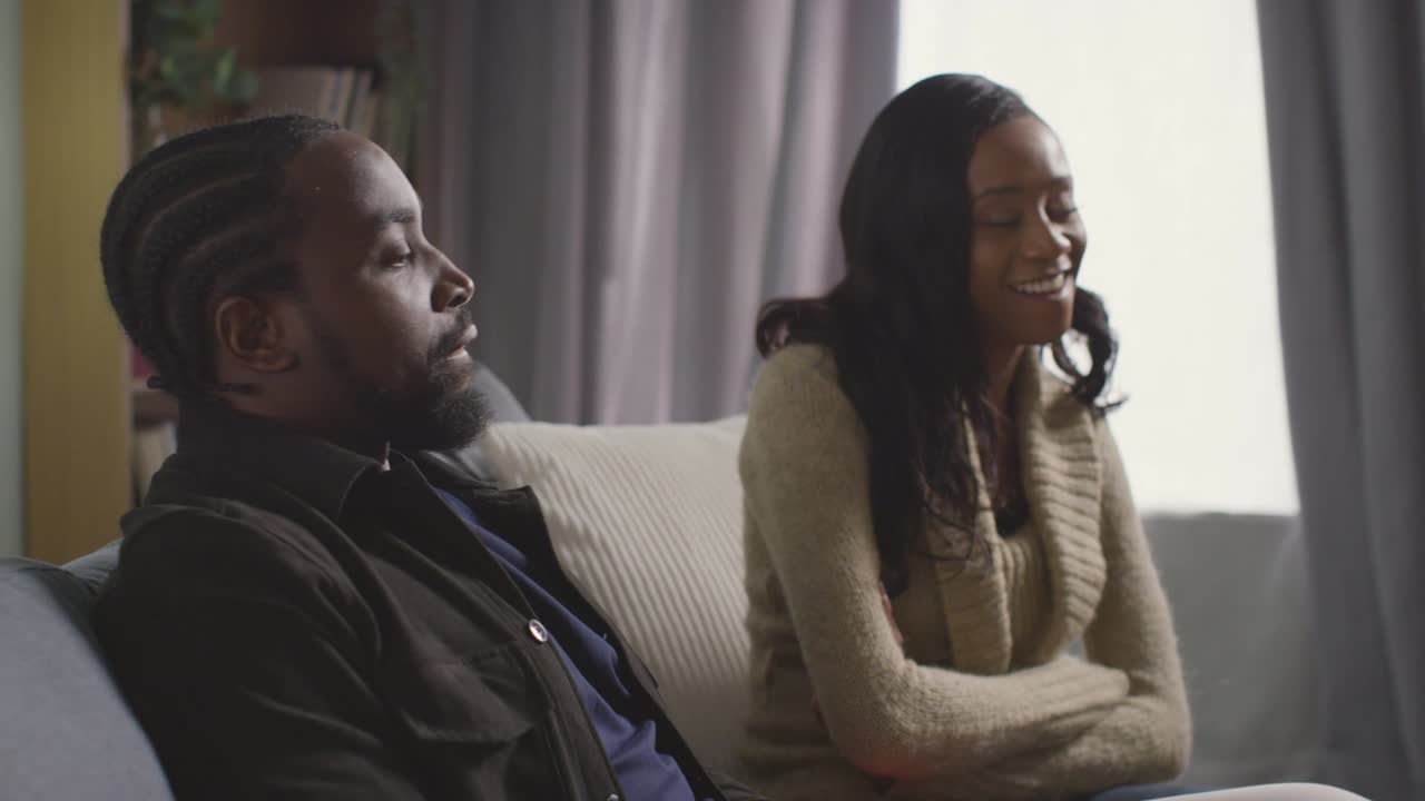 Couple At Home Sitting On Sofa In Lounge Having Break Up Argument 3