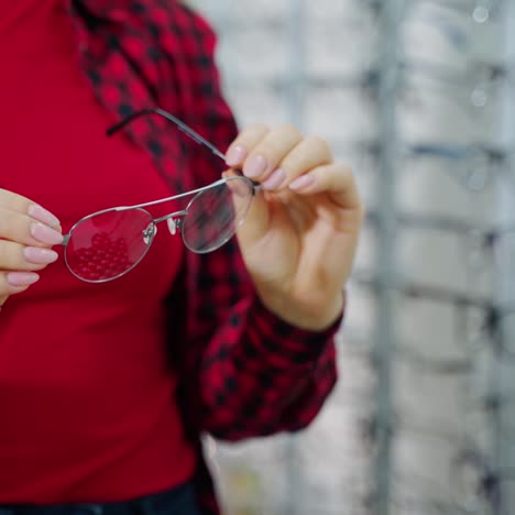 stylish eyeglasses in woman's hands. female buyer holding new spectacles in the optical store. close-up.