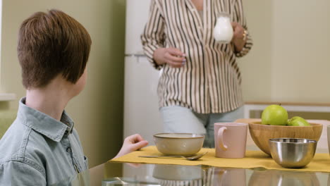 子供の朝食に牛乳を準備する女性