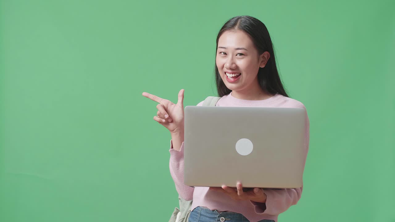 estudiante asiática usando una computadora portátil y dedos directos lado en el estudio de pantalla verde