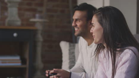 Couple-Relaxing-On-Lounge-Sofa-At-Home-And-Playing-Computer-Game-Together-With-Woman-Winning