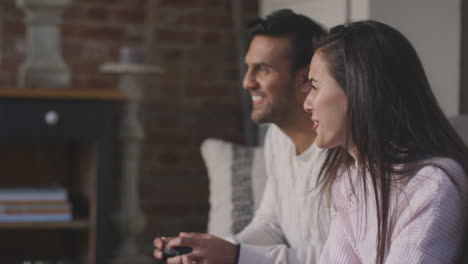 pareja relajándose en el sofá de la sala en casa y jugando a un juego de computadora juntos con la mujer ganadora