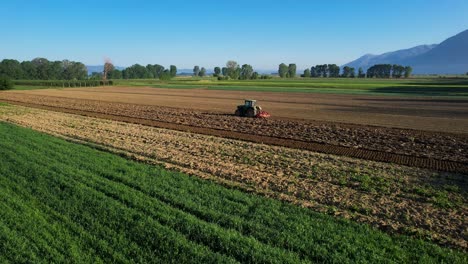 Tractor-Trabajando-Los-Campos-En-Hermosas-Parcelas-Agrícolas,-Cultivando-La-Tierra-Para-La-Agricultura-En-Una-Mañana-Soleada