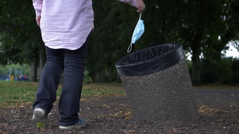 woman dropping face mask into a bin wide shot