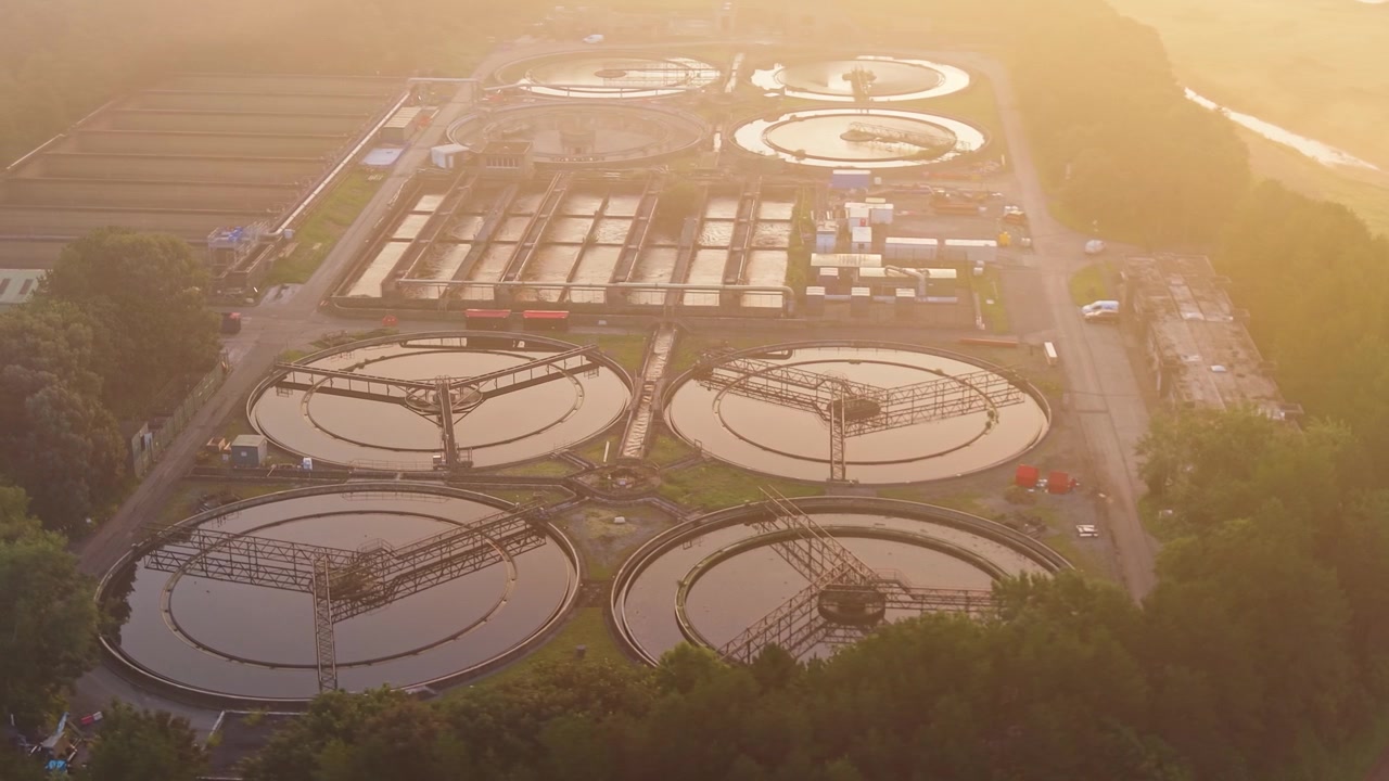 Overview of Water Treatment Plant and wastewater recycling facility at sunrise. Golden Hour glow over Secondary Clarifiers. Clean tech, sustainability, and environmental engineering concept.
