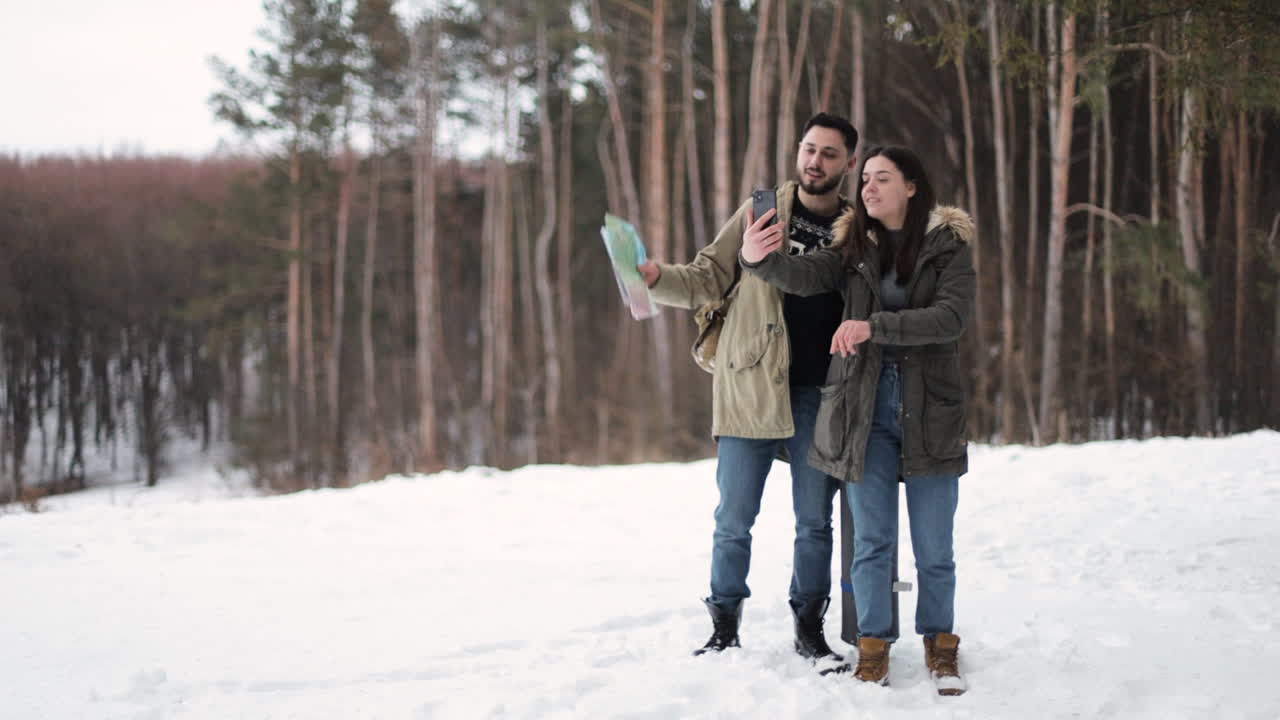 Kaukasisk par tager selfies i en sneklædt skov