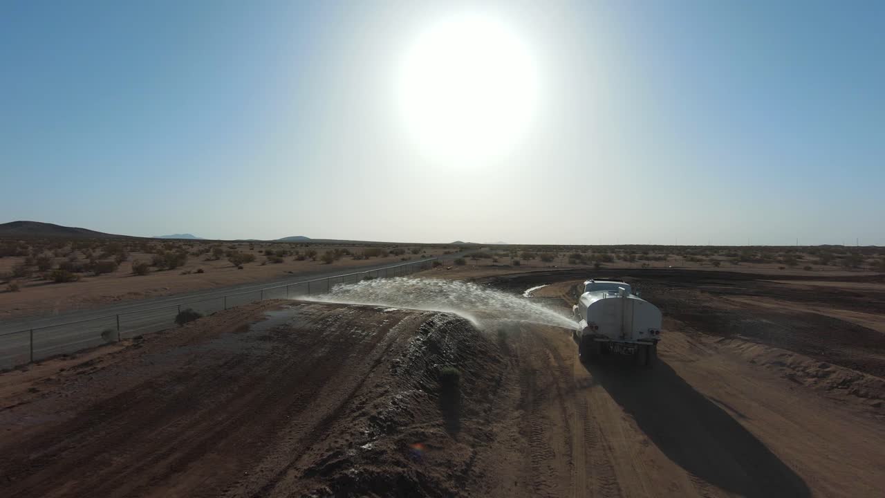 un camión cisterna de agua rocía una pista de tierra antes de la carrera de motocicletas - vista aérea