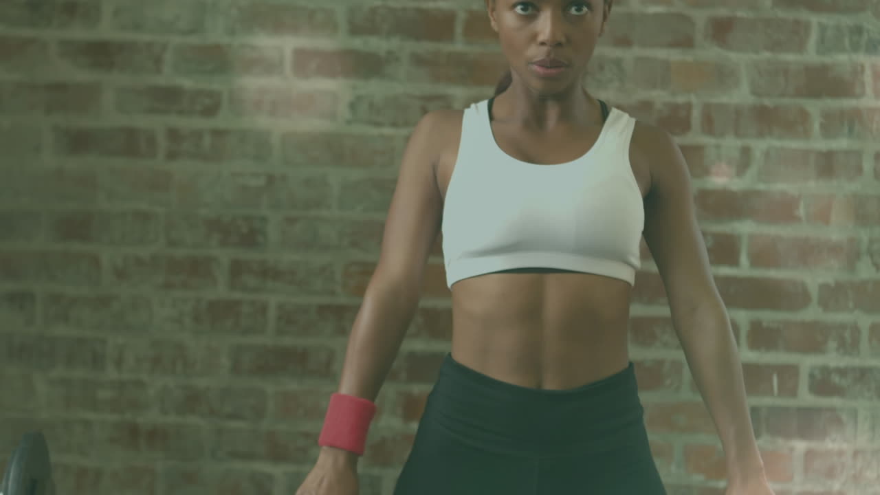 Animation of light spots over african american woman lifting weights at gym