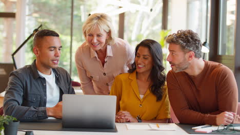 Equipo-De-Negocios-Multicultural-Reunido-Alrededor-De-Una-Computadora-Portátil-En-Una-Oficina-Moderna