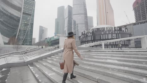 mujer subiendo las escaleras en un paisaje urbano en un día de nieve