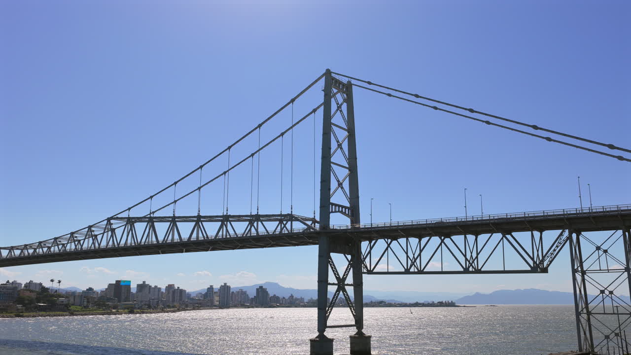 Aerial pullback revealing Hercilio Luz Bridge in Florianopolis, Brazil, iconic suspension structure over bay connecting city