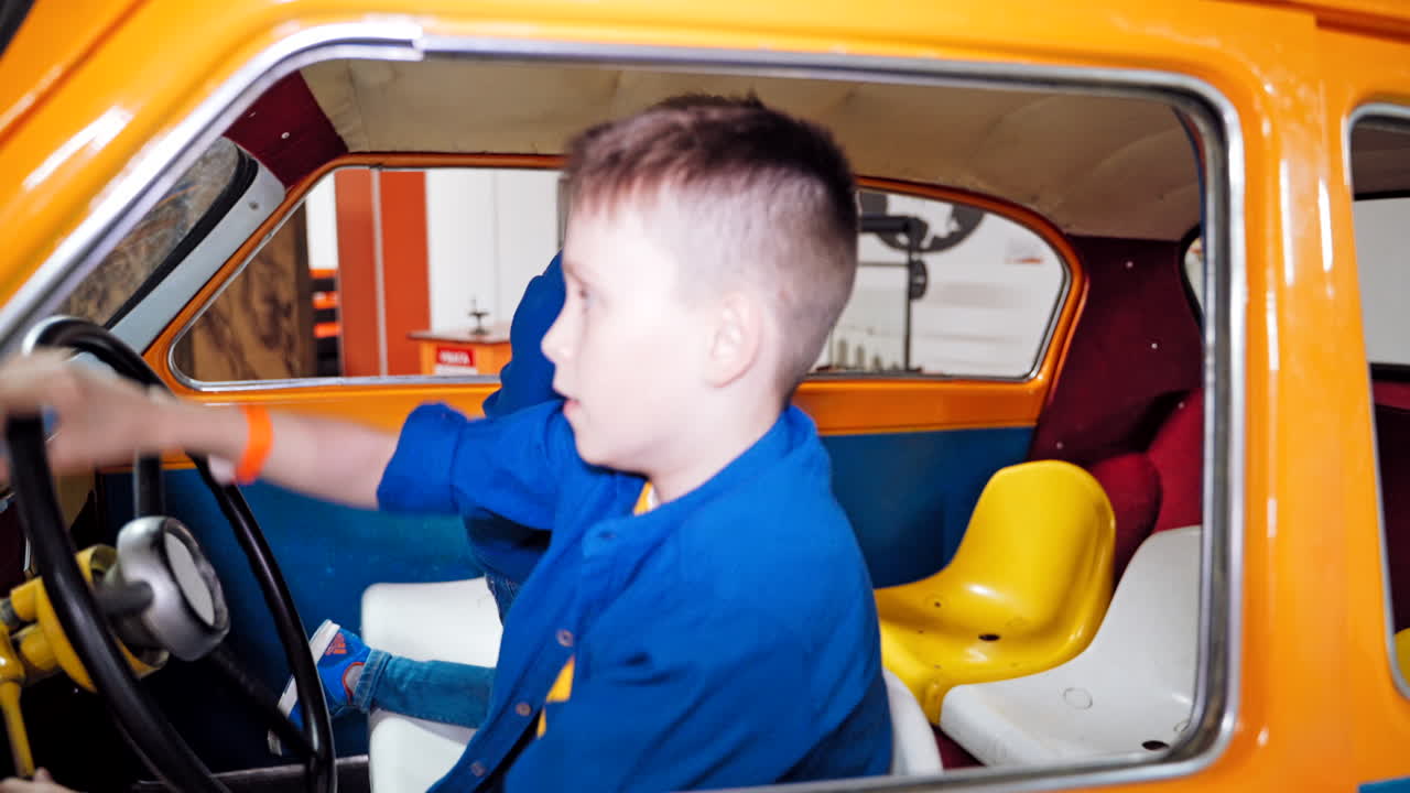 Little cheerful boy sits playing behind the wheel of a car. Baby's emotions