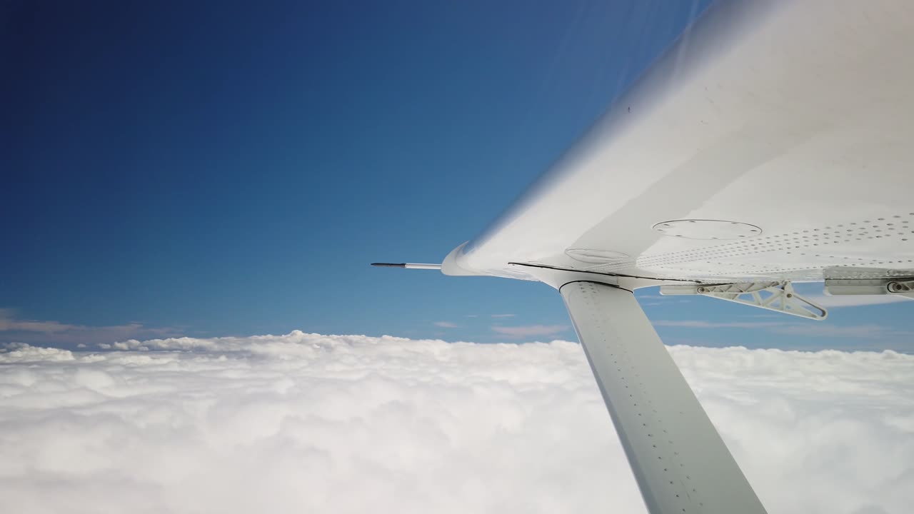 푹신한 흰 구름 푸른 하늘 위를 비행하는 작은 비행기 날개를 닫습니다