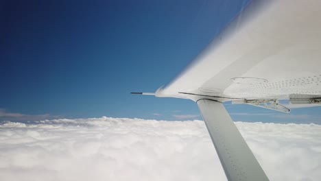 cerrar ala de avión pequeño volando por encima de nubes blancas hinchadas cielo azul