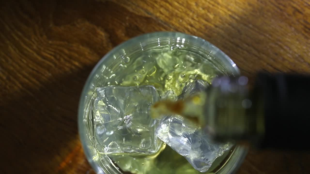 위에서 볼 때, 위스키가 얼음 큐브 위에 부어집니다.