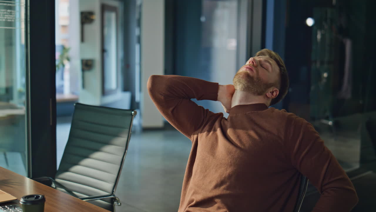 Tired worker closing laptop feeling neck pain at modern workplace closeup