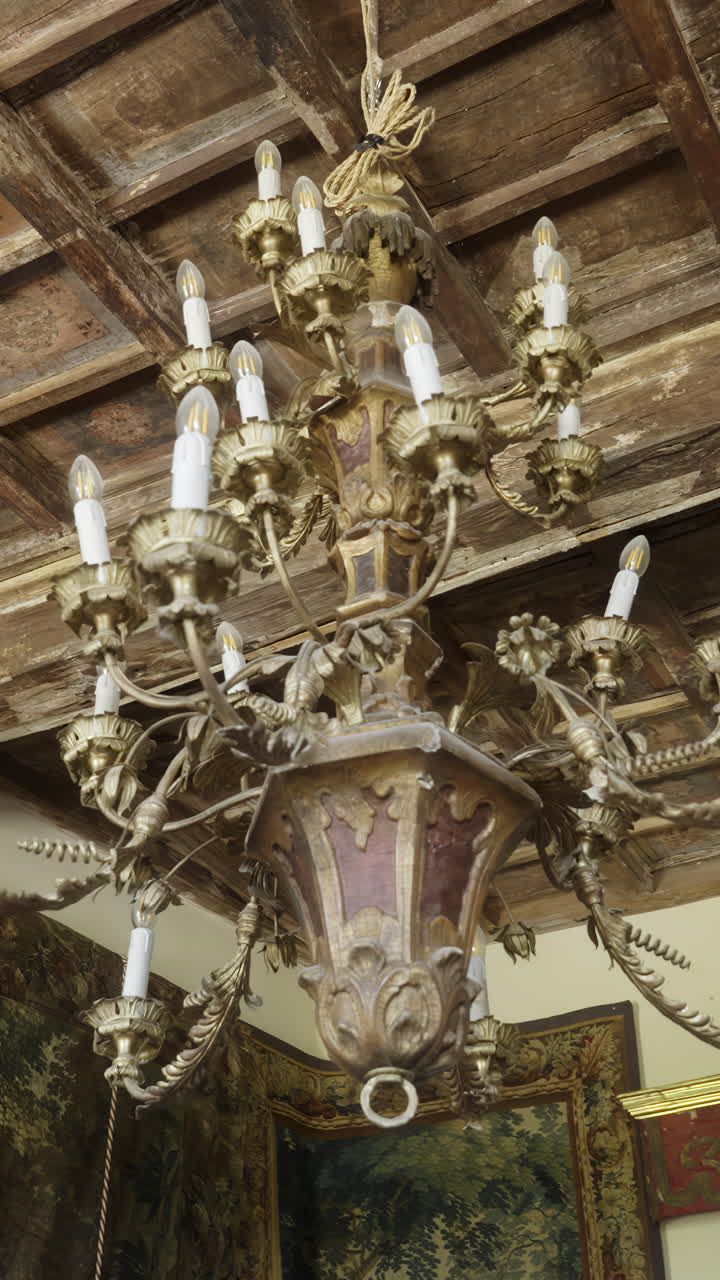 Ornate Golden Chandelier Hanging from an Antique Wooden Ceiling