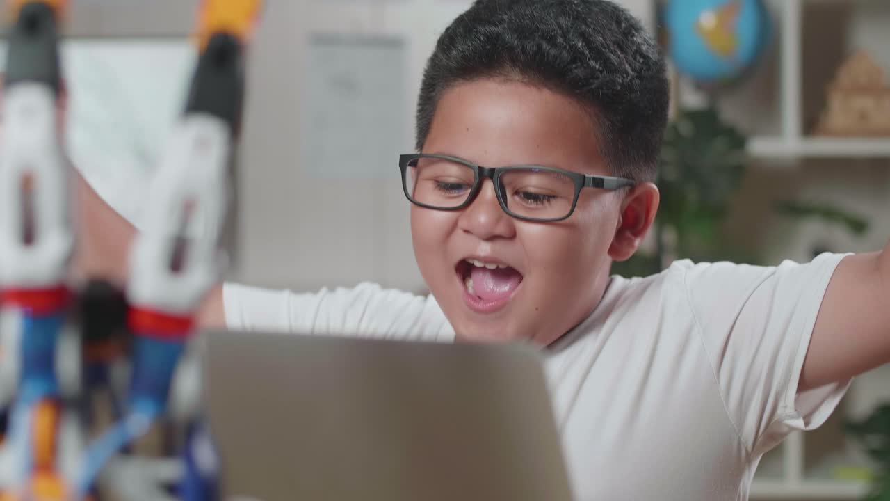 Close Up Of Asian Cute Boy Celebrating Succeed Working About A Cyborg Hand On A Laptop At Home