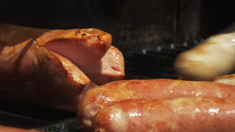 barbacoa parrilla salchichas listo caliente humo mano volteando primer plano jugoso