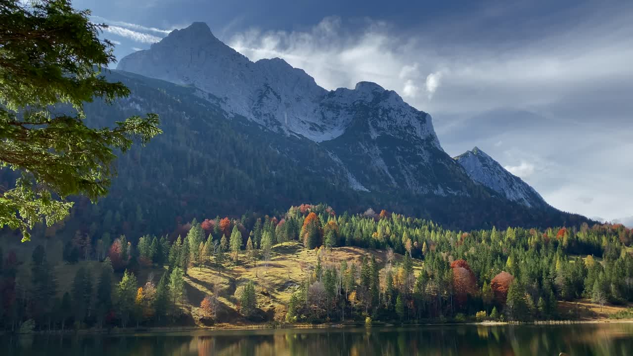 luz teatral de otoño del lago ferchen con el bosque dorado de otoño y la montaña grünkopf al fondo, muy cerca de la ciudad bávara de mittenwald en alemania