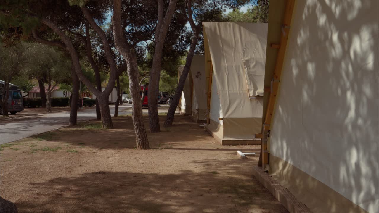 Prázdné glampingové stany pod stromy v letním kempu