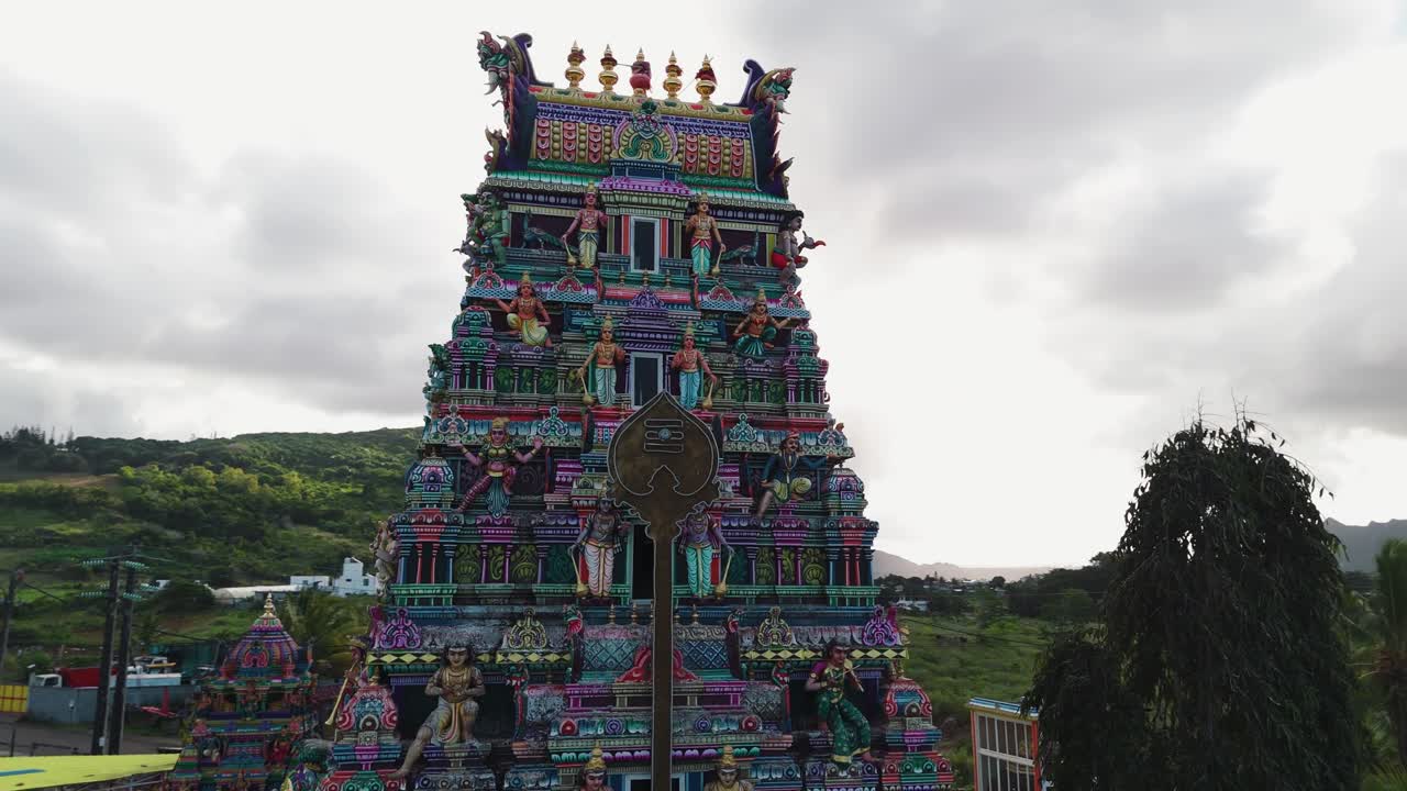 Front of Tamil Hindu temple entrance with tall gopuram decorated in bright colors and figures, detailed closeup