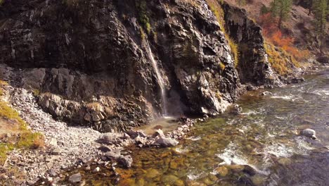 aerial drone shot flying in from up river towards a waterfall hot spring in the boise national forest idaho