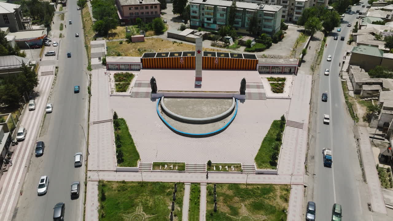 Tráfico en las calles con el Monumento del Parque Pobedy en Istaravshan, Tayikistán