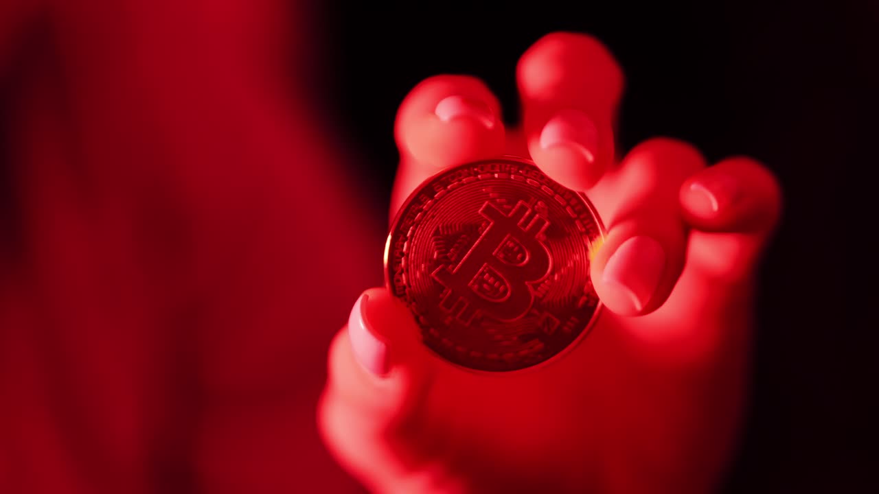 Woman holding Bitcoin coin under red light, cryptocurrency power, slow motion