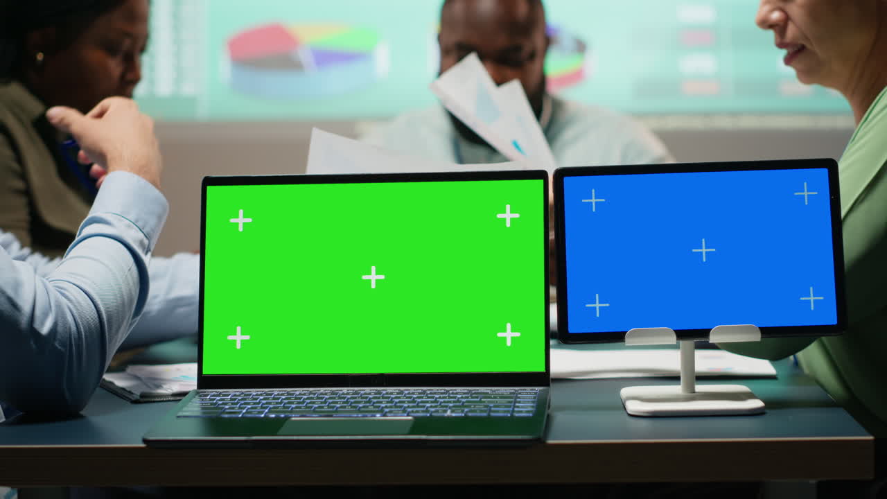 Company associates briefing after hours next to chroma key screen