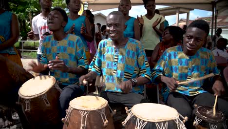 three drummers drum joyfully at the yam festival in rural ho, ghana, west africa.