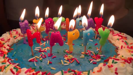coloridas velas de feliz cumpleaños iluminadas en un colorido pastel con glaseado azul y chispas de arco iris