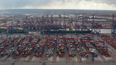 Aerial-dolly-view-of-colorful-containers-and-large-cargo-cranes-in-industrial-port-in-Hamburg,-Germany