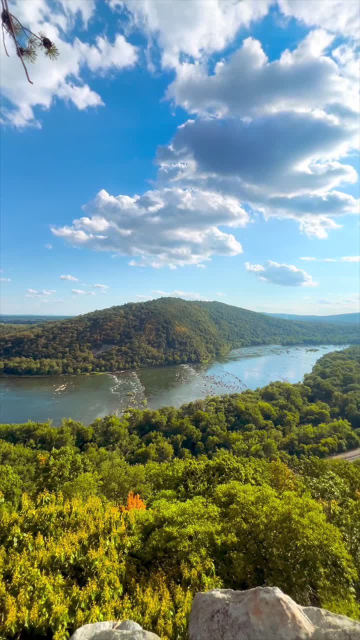 Panning shot standing on a mountain with a river valley below. Sunny day