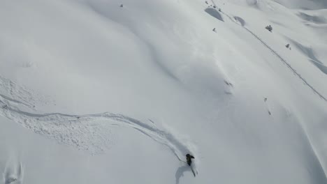 Aerial-of-young-people-sports-skiing-down-snow-covered-glacier-mountain-range-scnery