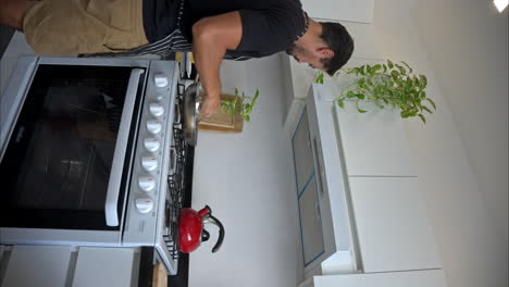 movimiento lento vertical de un hombre latino mexicano en forma cocinando mientras escucha una canción bailando y cantando teniendo un gran momento a solas