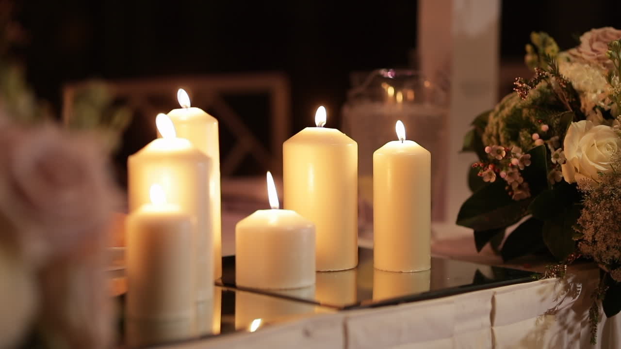 Candles burning next to rose flower arrangement, panning