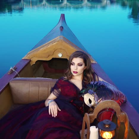 a charming woman in a red dress is riding in the gondola in the evening. carnival in venice. blue background