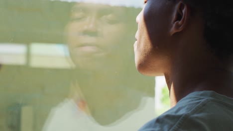 african american man looking at the window and drinking coffee at home