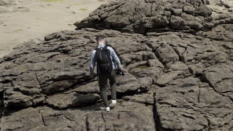 man hiking on rocky coastline beach