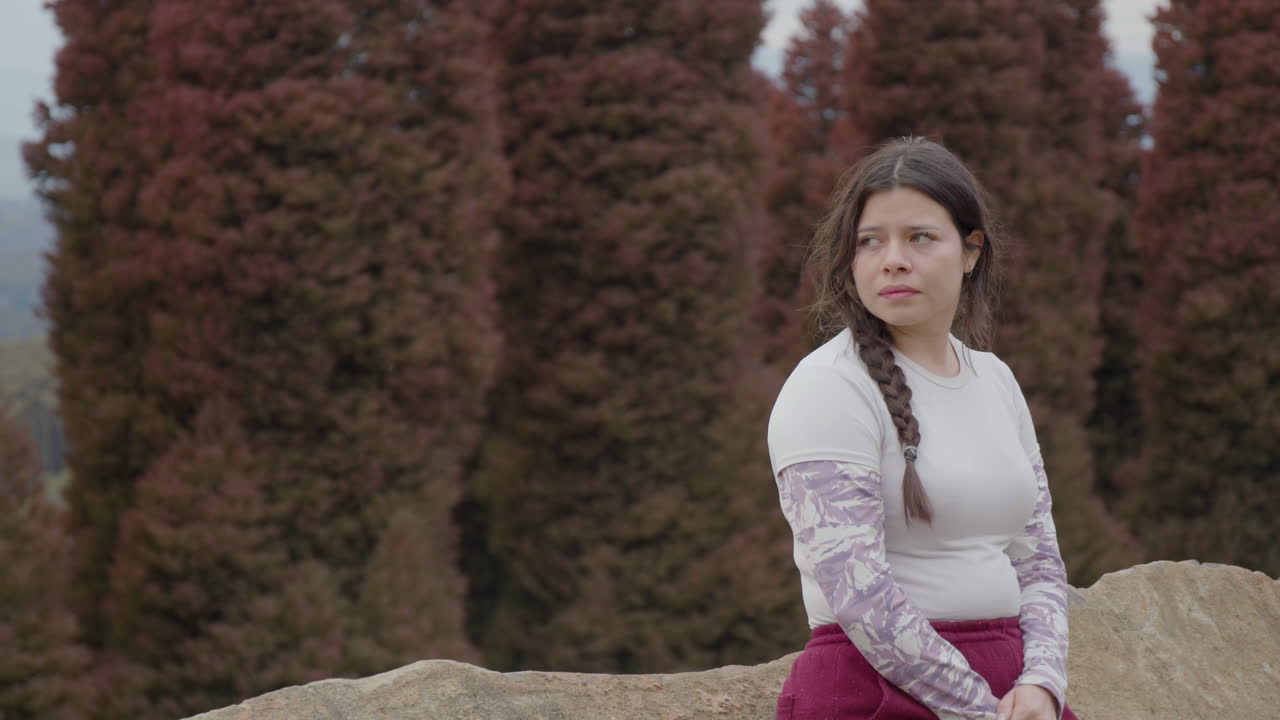 A young woman seems slightly down in the dumps as she looks around the park, all by herself