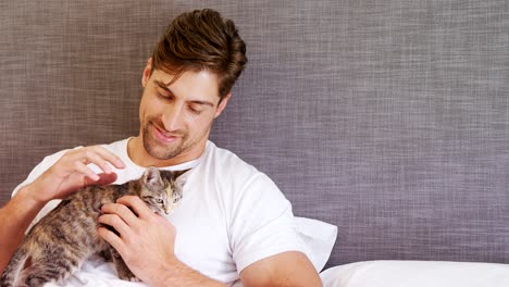 young man sitting on bed stroking his tabby cat 4k 4k