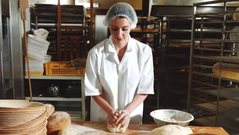 female baker kneading a dough