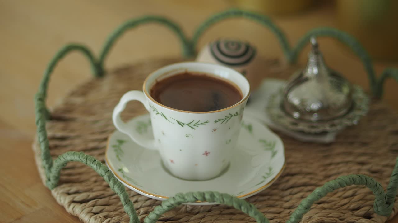 A close-up of a cup of Turkish coffee on a woven tray