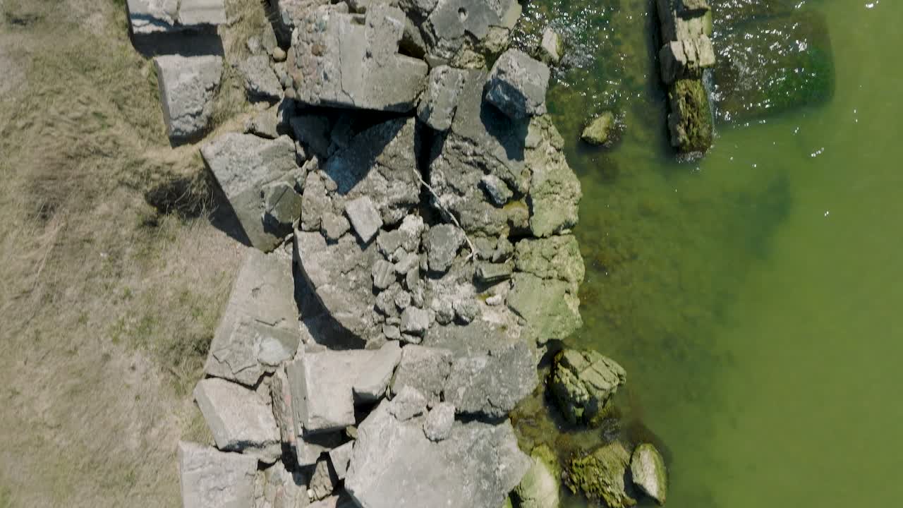 Splendida veduta aerea panoramica delle rovine delle fortificazioni costiere in cemento di Karosta, mare Baltico calmo, giornata estiva di sole, ripresa drone a volo d'uccello in avanzamento