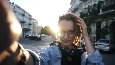 una joven con gafas posa con una cámara en la mano extendida